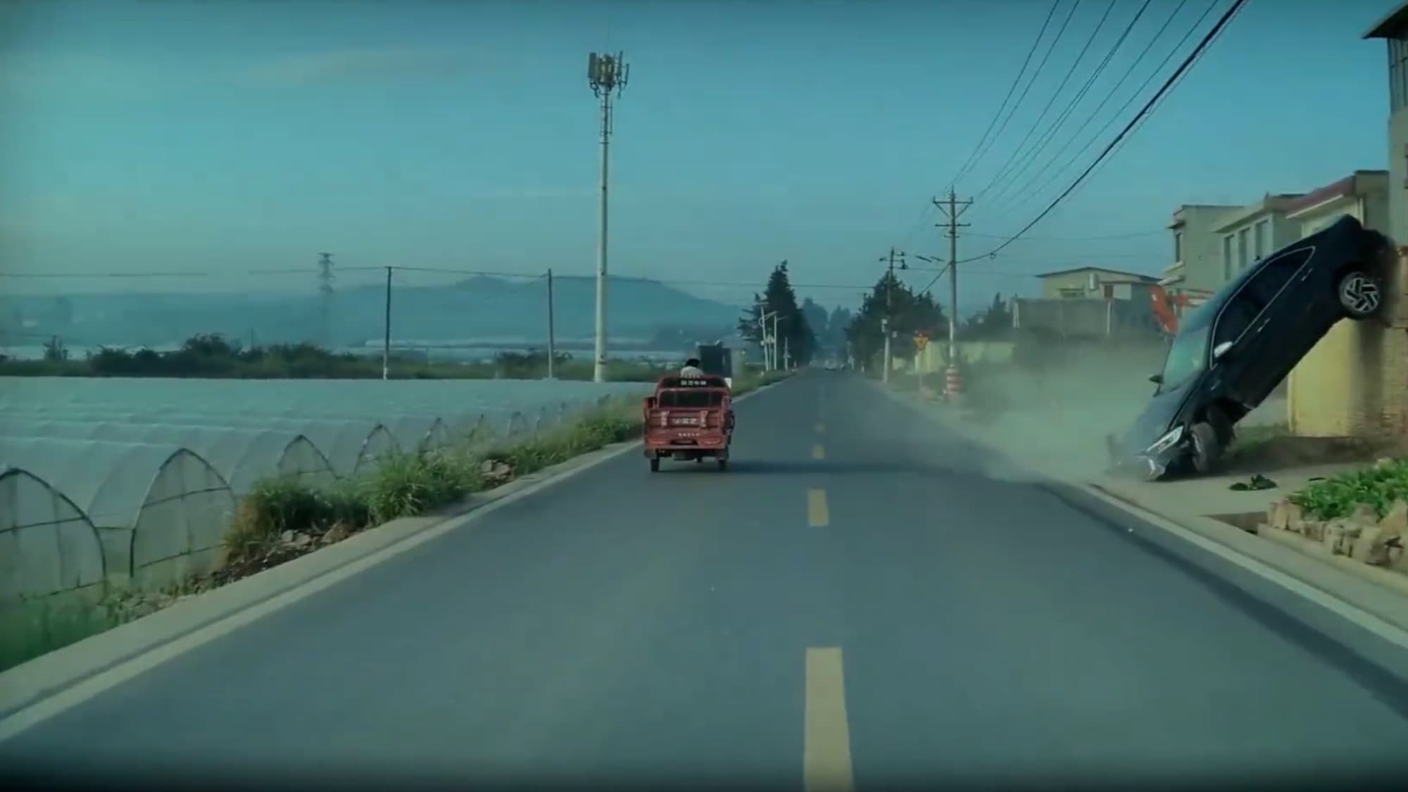 Car goes off road, flies into the air and gets caught on wall in Yunnan, China. No one was harmed. Note: Photo is a screenshot from a video. (AsiaWire/NX)